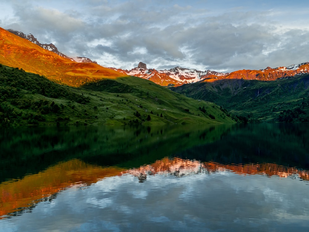 green and brown mountains near lake under white clouds during daytime