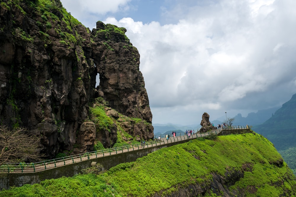 people walking on gray concrete bridge near brown rock formation during daytime