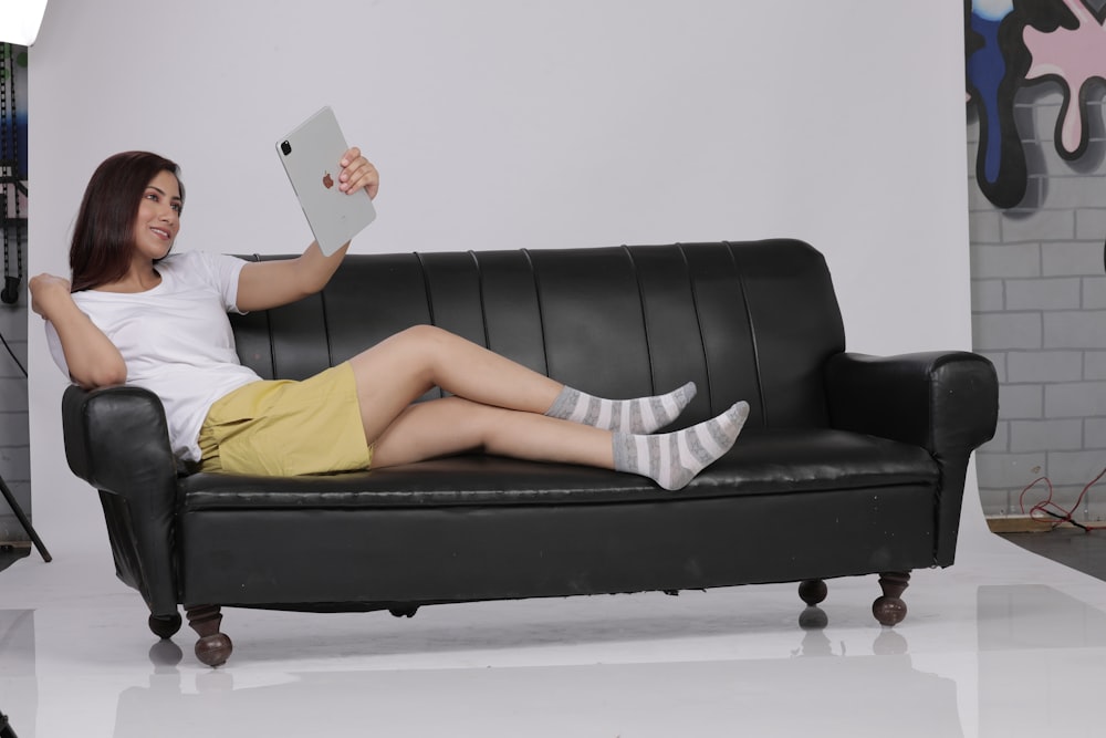 woman in yellow shirt lying on black couch