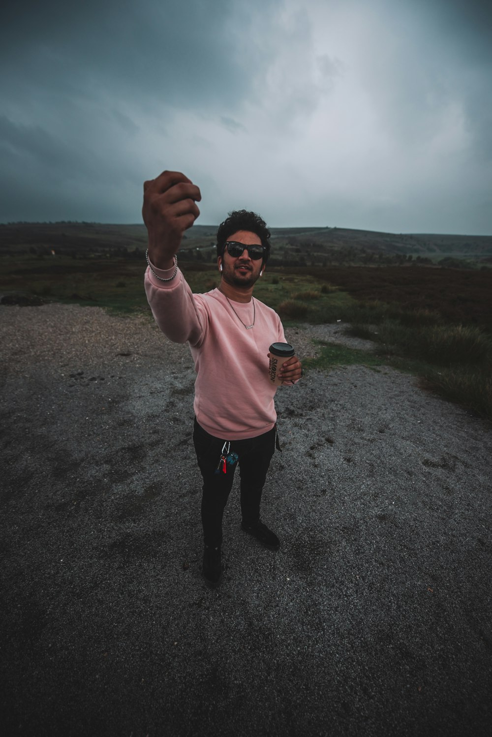 woman in pink long sleeve shirt and black pants standing on gray sand during daytime