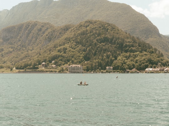 person riding on boat on sea near mountain during daytime in Lac d'Annecy France