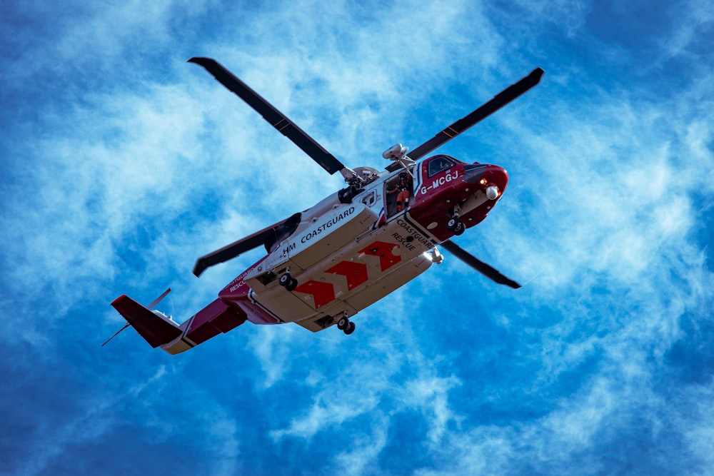 red and white helicopter flying in the sky