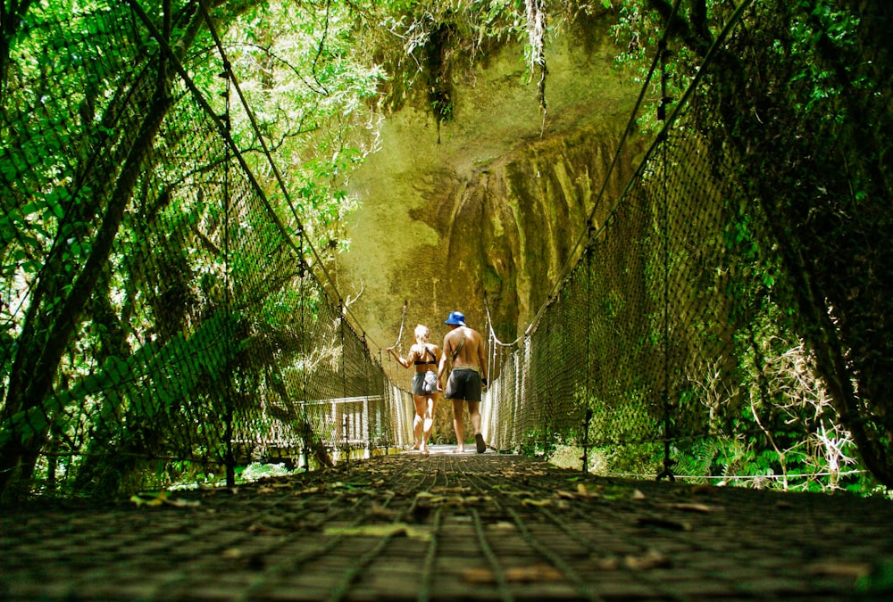 2 men walking on brown wooden pathway