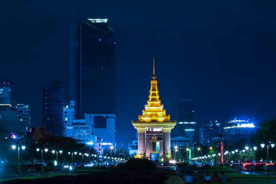 white and gold concrete building during night time in Statue of King Father Norodom Sihanouk Cambodia