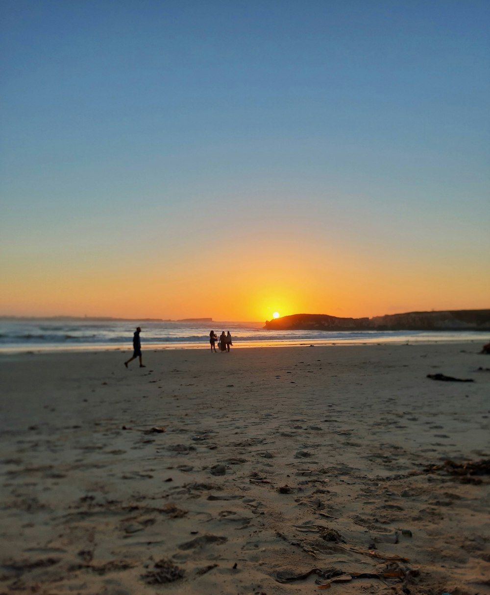pessoas na praia durante o pôr do sol
