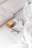 A cozy setting with a neatly made bed featuring a soft white comforter and pillows. On the bed, there is a stack of white paper with a minimalist green design on it, accompanied by a pair of tortoiseshell glasses. A warm brown ceramic mug is also placed beside the papers.