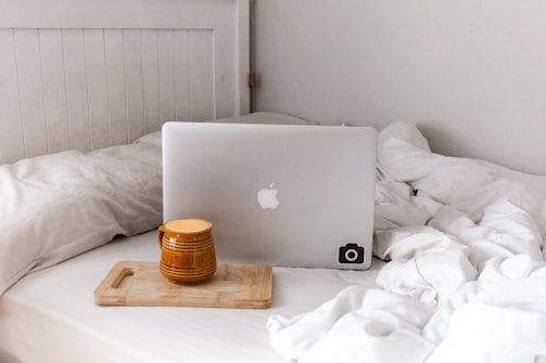 A warm, inviting desk with a laptop, a cup of tea, and soft bedding samples nearby.