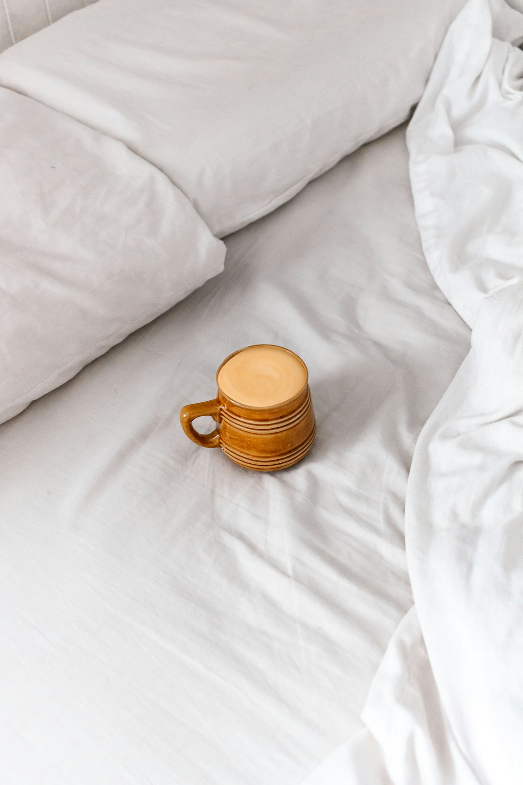 brown ceramic mug on white textile