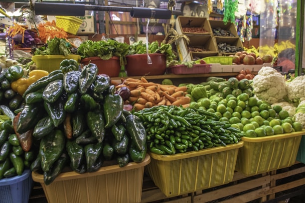 A vibrant Mexican market stall showcasing fresh avocados, berries, and colorful vegetables.