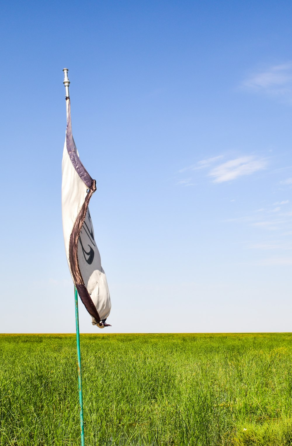 black and white flag on green grass field under blue sky during daytime