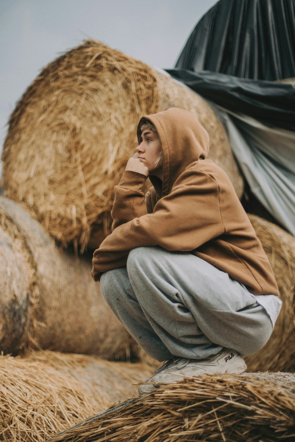 woman in brown jacket and gray pants sitting on brown fur textile