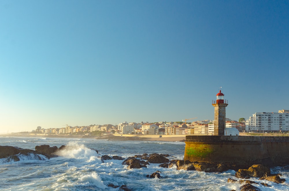 red and white lighthouse on rocky shore during daytime