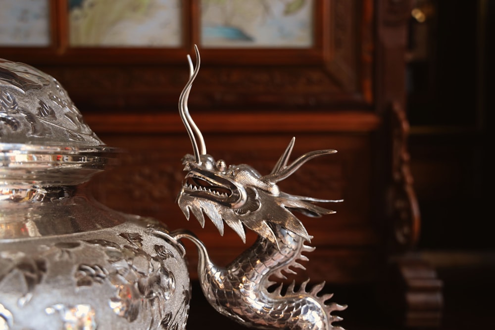 silver dragon figurine on brown wooden table