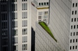 Tall modern buildings with numerous windows and a green rooftop garden situated on one of the structures.