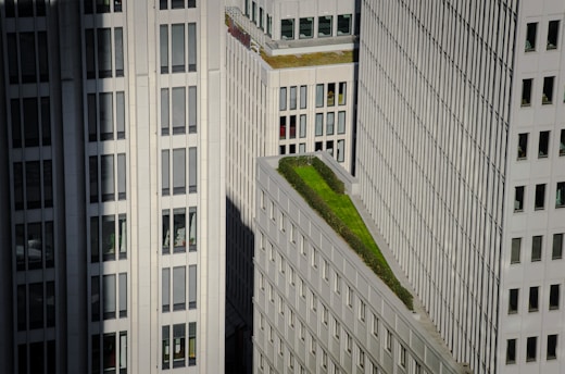 Tall modern buildings with numerous windows and a green rooftop garden situated on one of the structures.