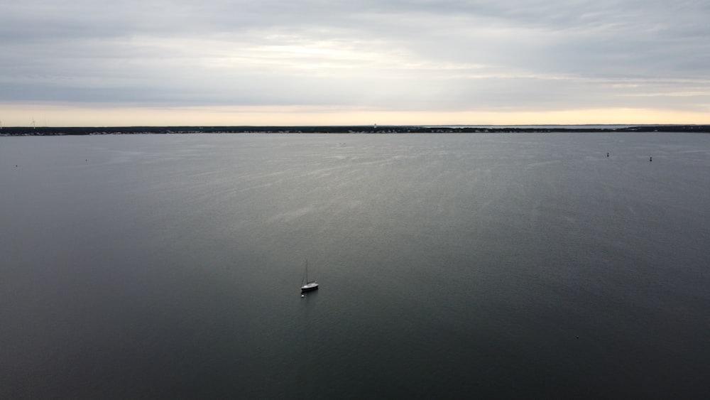 boat on calm sea under white clouds during daytime