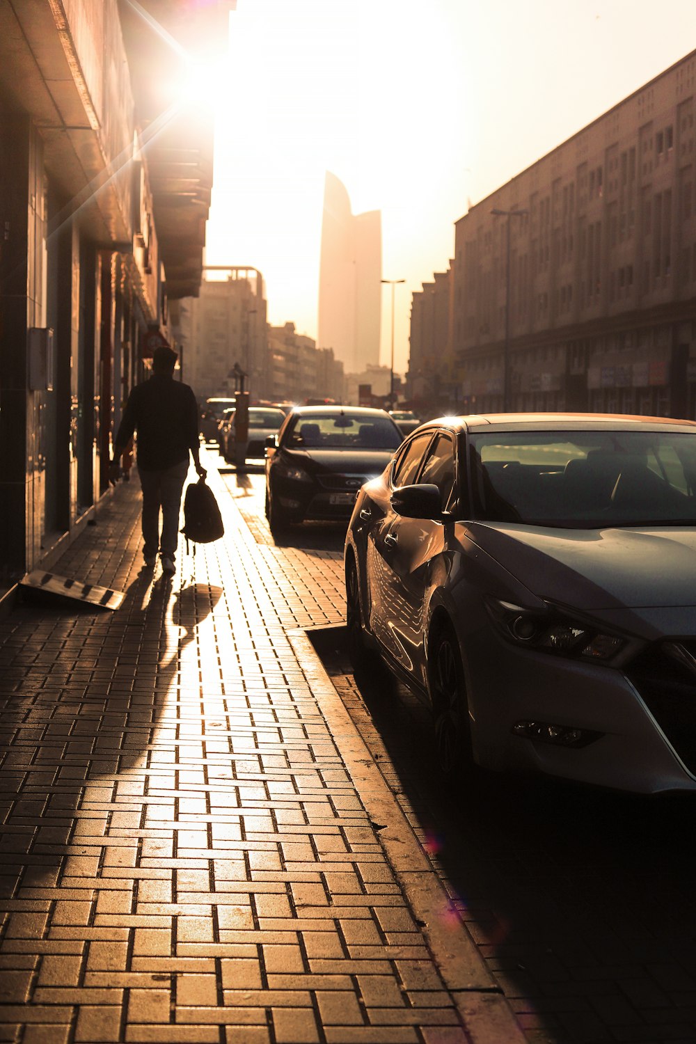 man in black jacket and pants walking on sidewalk during daytime