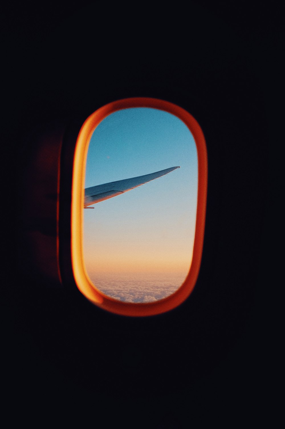 airplane window view of orange and white cloudy sky during daytime