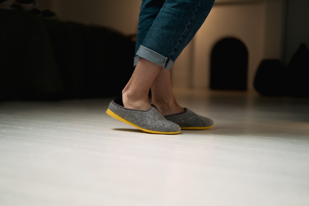 person in blue denim jeans and grey and yellow slip on shoes