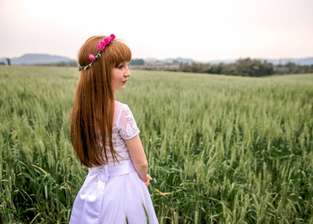 girl in white dress standing on green grass field during daytime