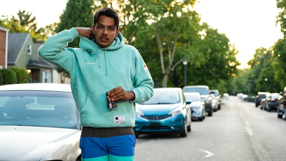 man in green hoodie standing near cars during daytime