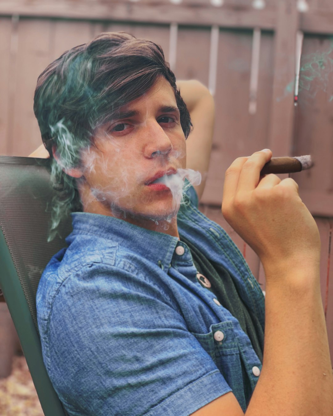 man in blue denim button up shirt smoking cigarette
