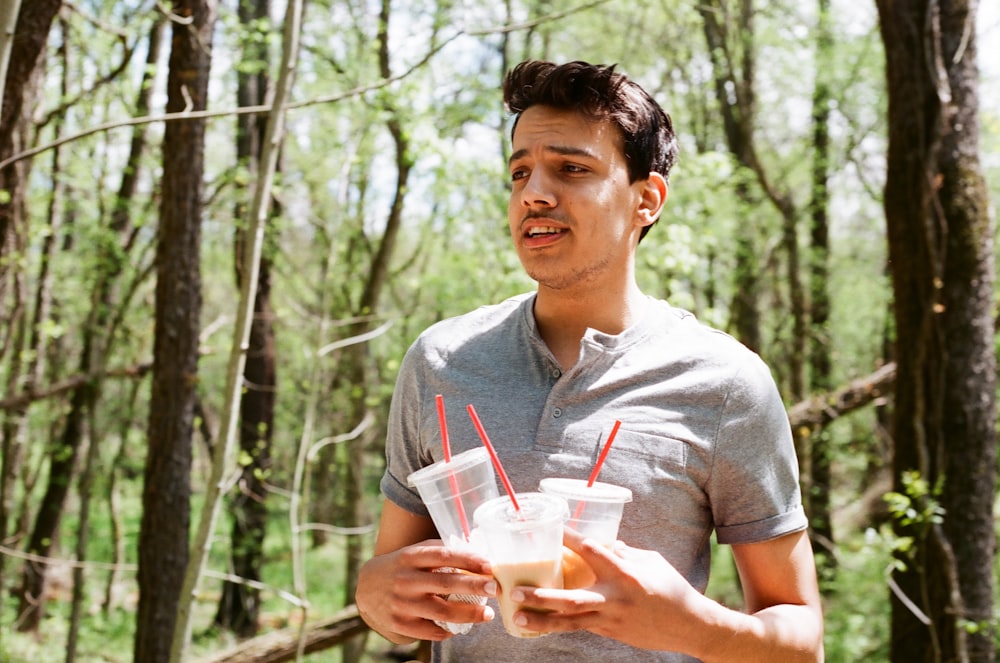 man in gray polo shirt holding clear plastic cup