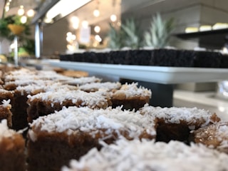 Close-up of a moist tapioca cake slice on a rustic wooden plate with a sprinkle of coconut flakes