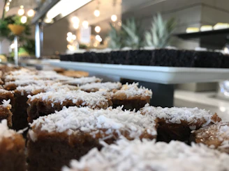 Warm, inviting close-up of tropical bite-size desserts arranged on a rustic wooden table.