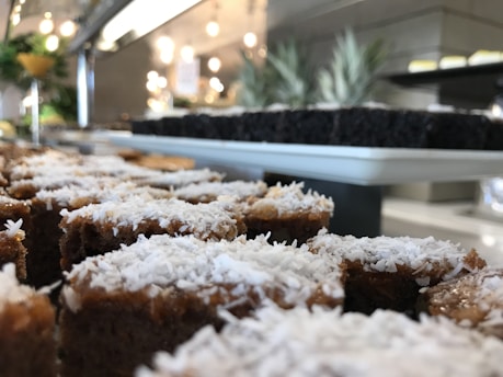 Close-up of a moist tapioca cake slice on a rustic wooden plate with a sprinkle of coconut flakes