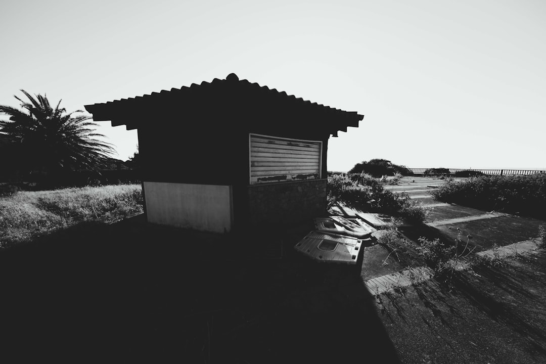 grayscale photo of wooden house on rocky field