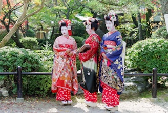 2 women in red and blue floral kimono standing on white sand during daytime
