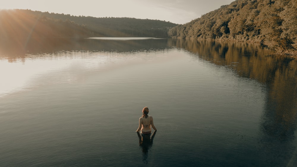 woman in black dress standing on lake during daytime