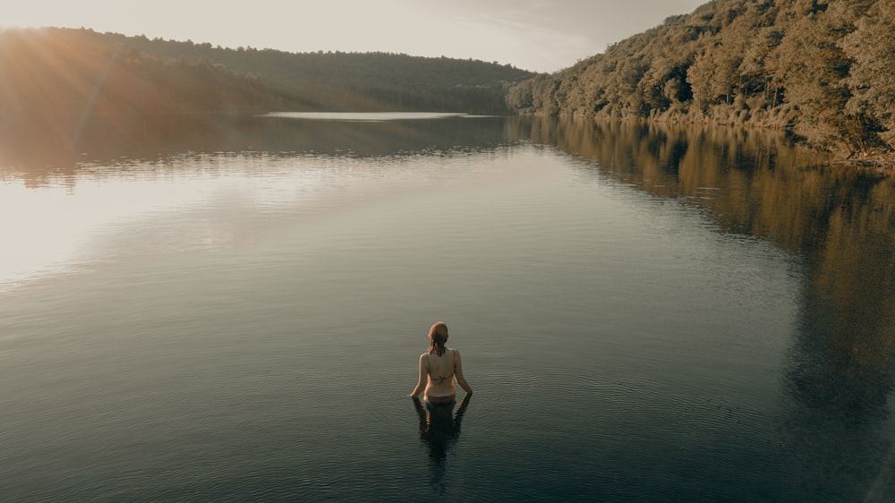 donna in abito nero in piedi sul lago durante il giorno