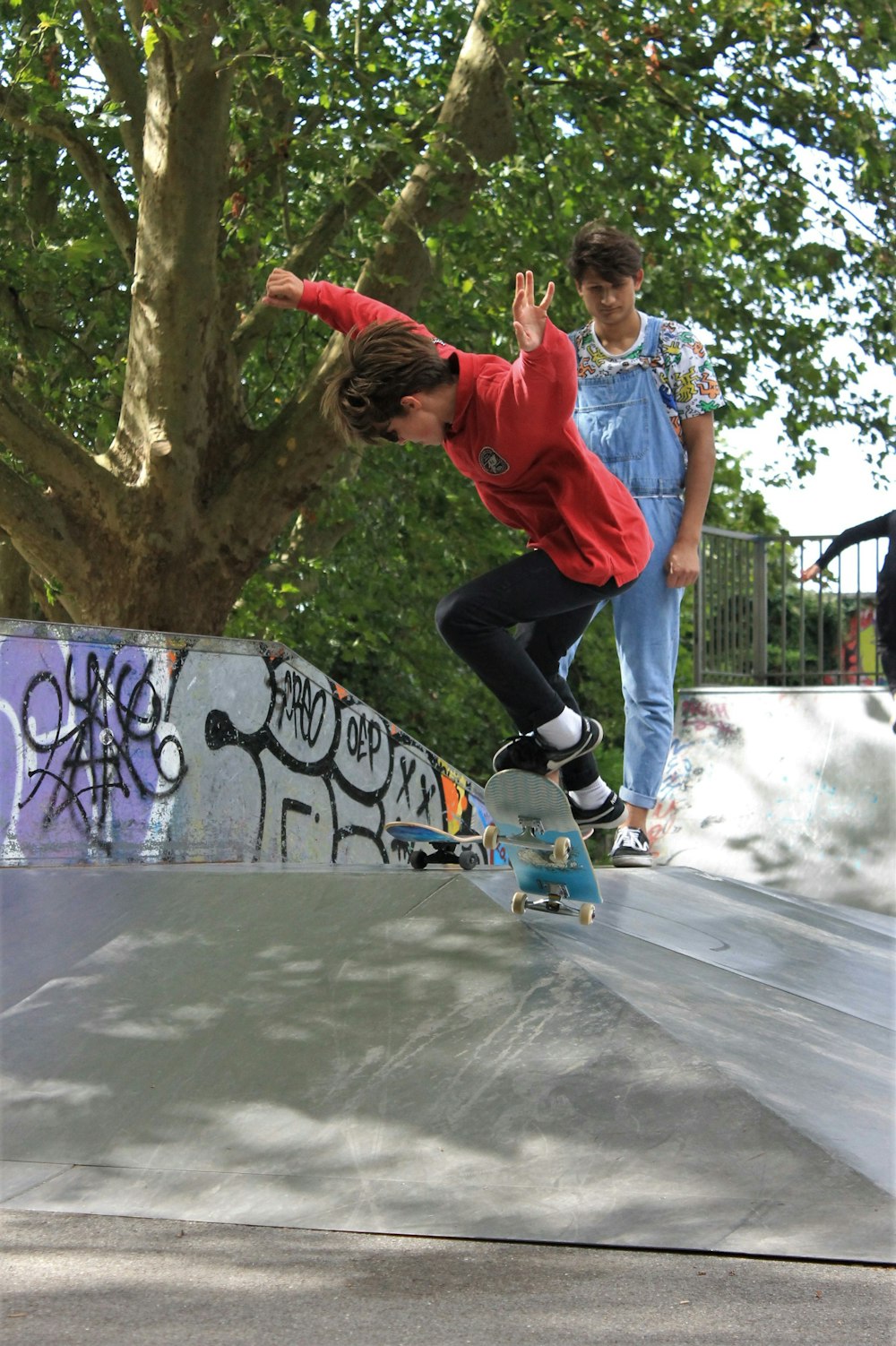 boy in red t-shirt and black pants playing with blue and white nike shoes