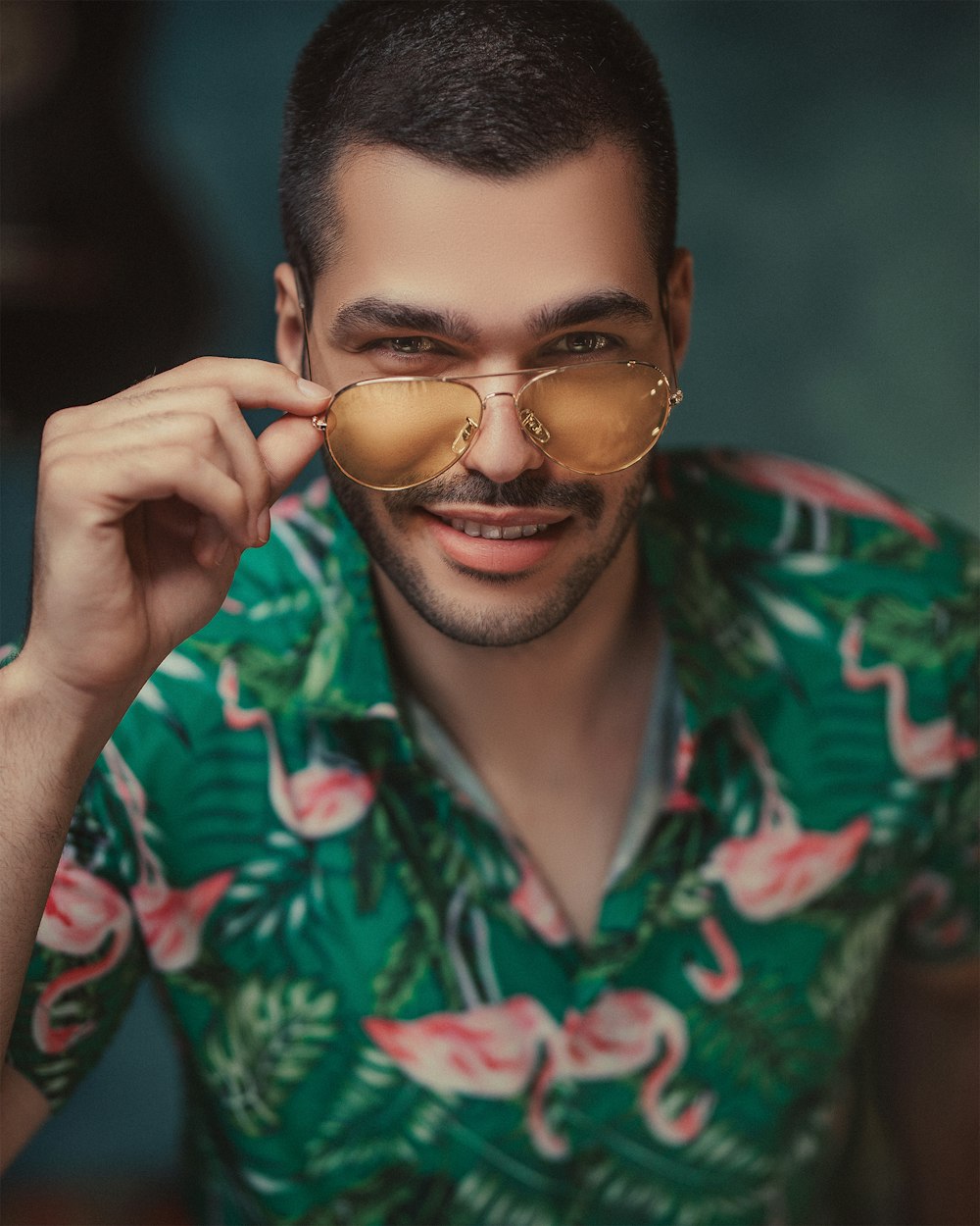 man in green and red floral button up shirt wearing gold framed sunglasses