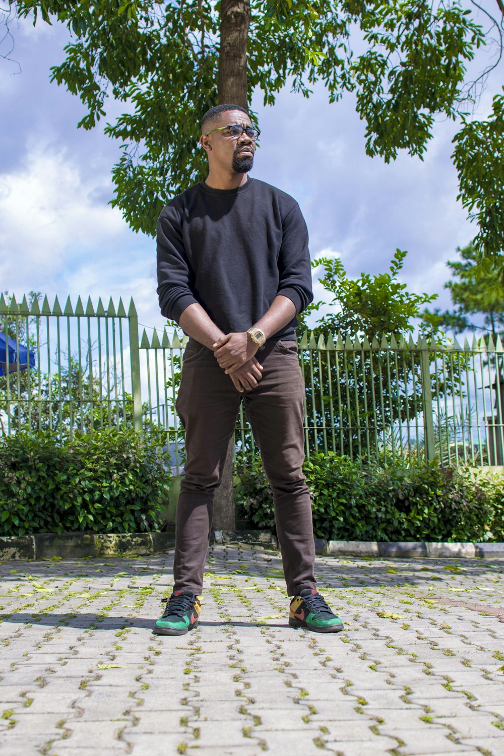 man in black long sleeve shirt and brown pants standing on brick floor