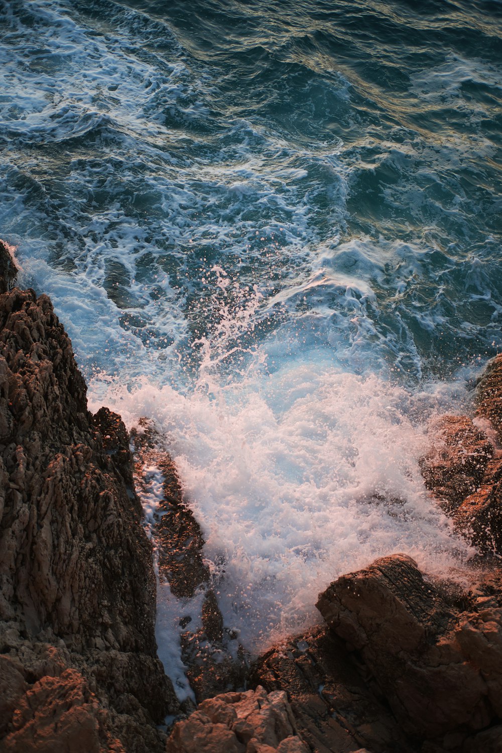 water waves hitting brown rocky shore during daytime