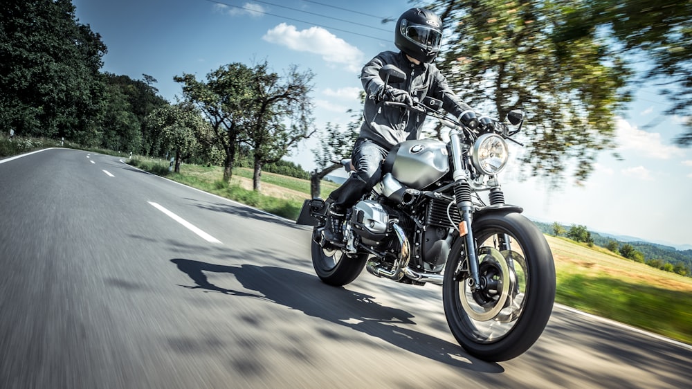 man in black and gray motorcycle helmet riding motorcycle on road during daytime