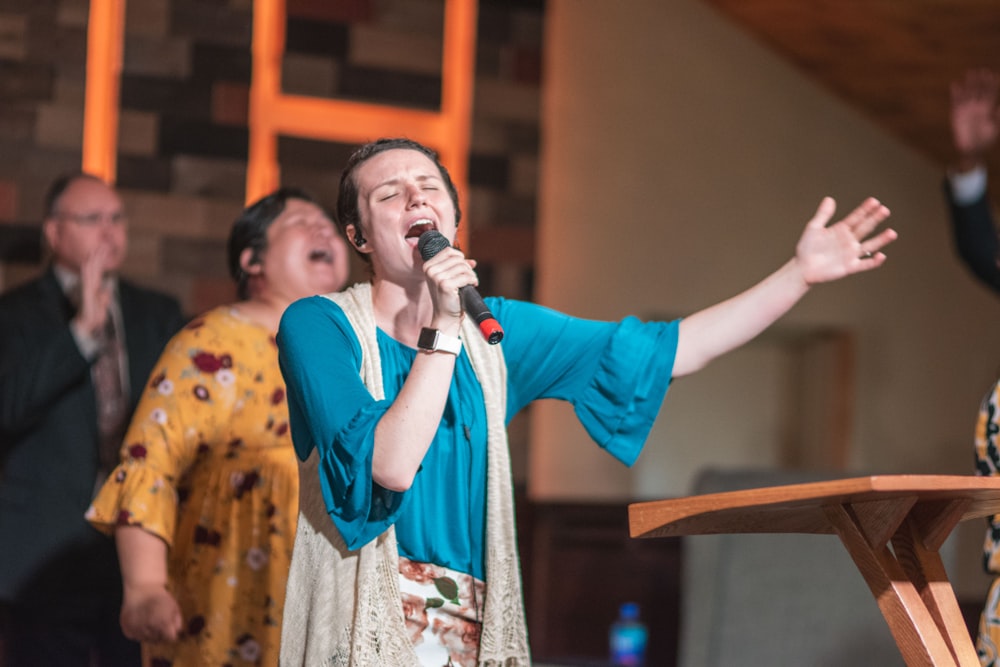 woman in blue long sleeve shirt holding microphone