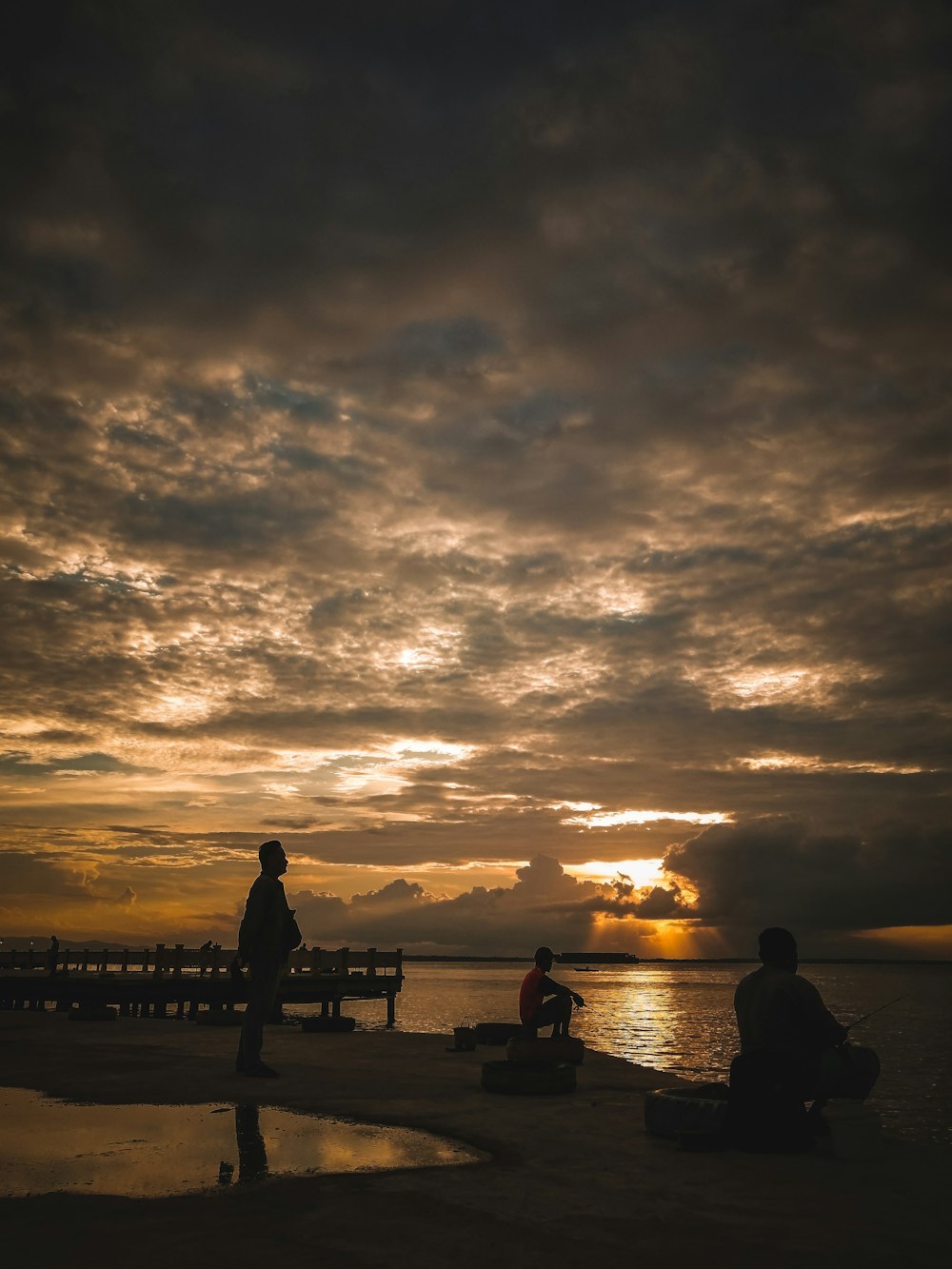 silhouette di persone in piedi sul molo durante il tramonto