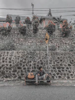 A serene outdoor scene with Kentenfromlucca sitting on a bench, guitar in hand.