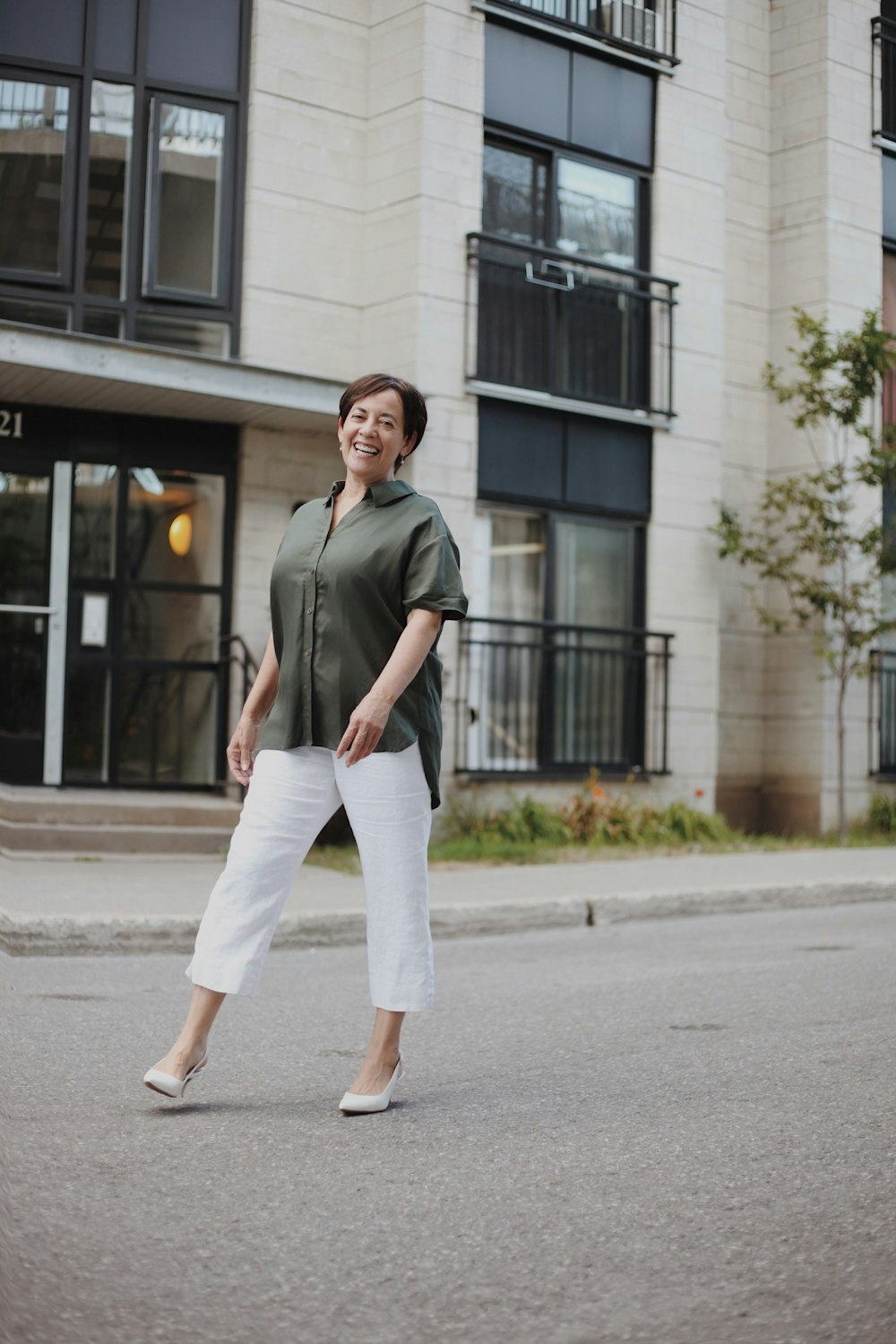 man in green button up shirt and white pants standing on sidewalk during daytime