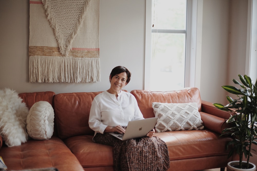 man in white dress shirt sitting on red couch using macbook