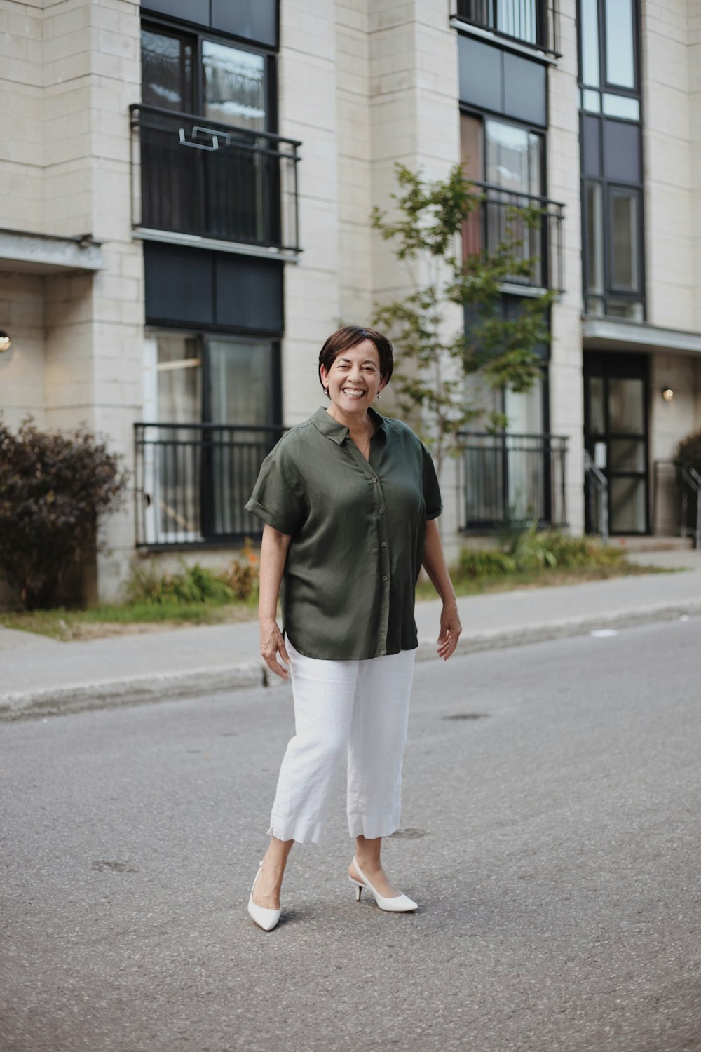 man in gray polo shirt and white pants standing on gray asphalt road during daytime