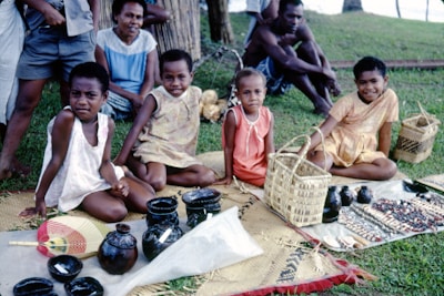 Children engaged in a traditional craft workshop outdoors surrounded by lush greenery