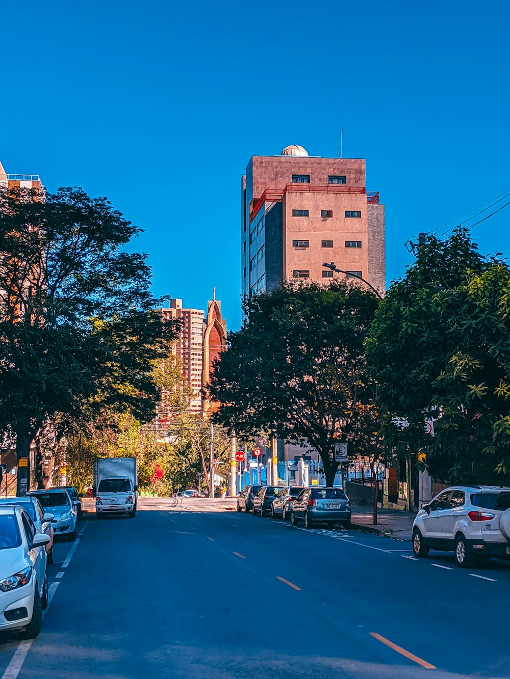 carros estacionados no lado da estrada perto de arranha-céus durante o dia