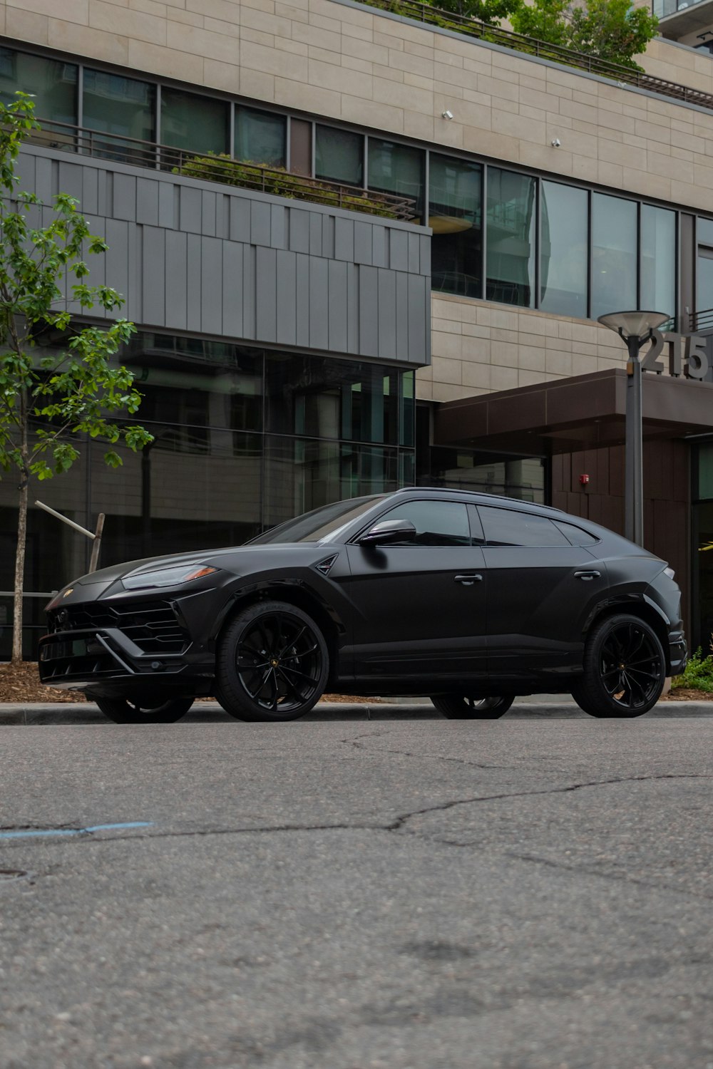 black sedan parked near green tree during daytime