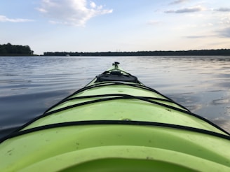 A calm lake at sunrise with a kayak gently floating near the shore.