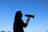 A silhouette of a person holding a megaphone against a clear blue sky, suggesting communication or a call to action.